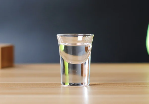 Ly nước đặt trên bàn, phía sau là nền màu xanh đậm.